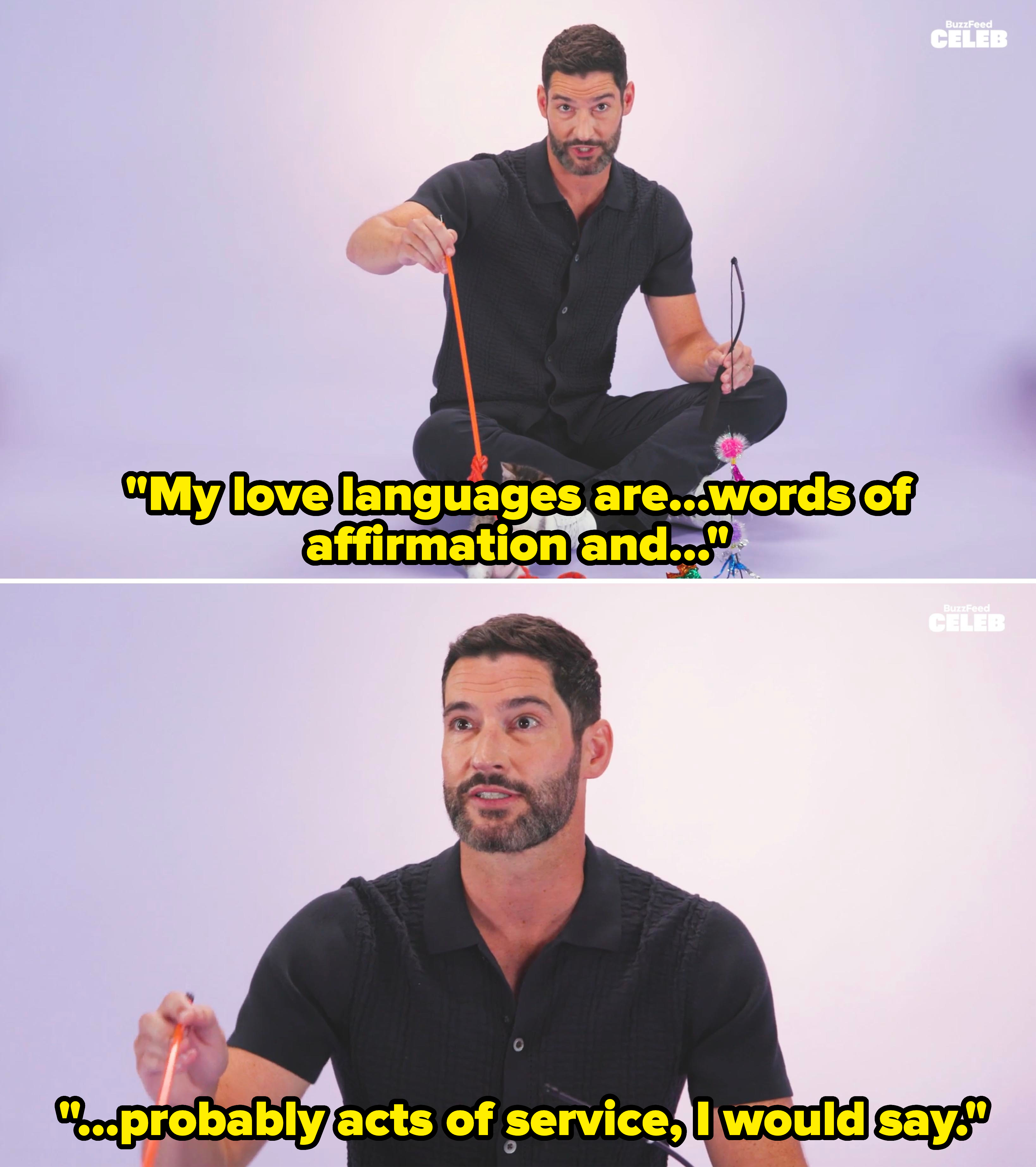 Tom Ellis playing with a kitten using various toys, sitting cross-legged in a casual black outfit