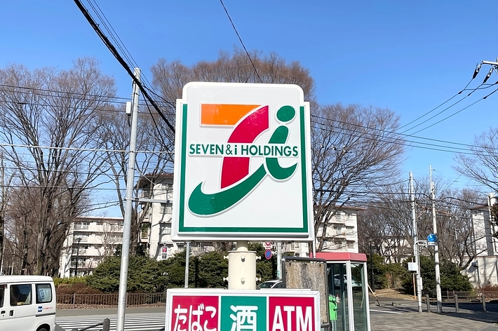 セブン-イレブンの看板。上には「SEVEN & i HOLDINGS」、下には「たばこ、酒、ATM」の表示。