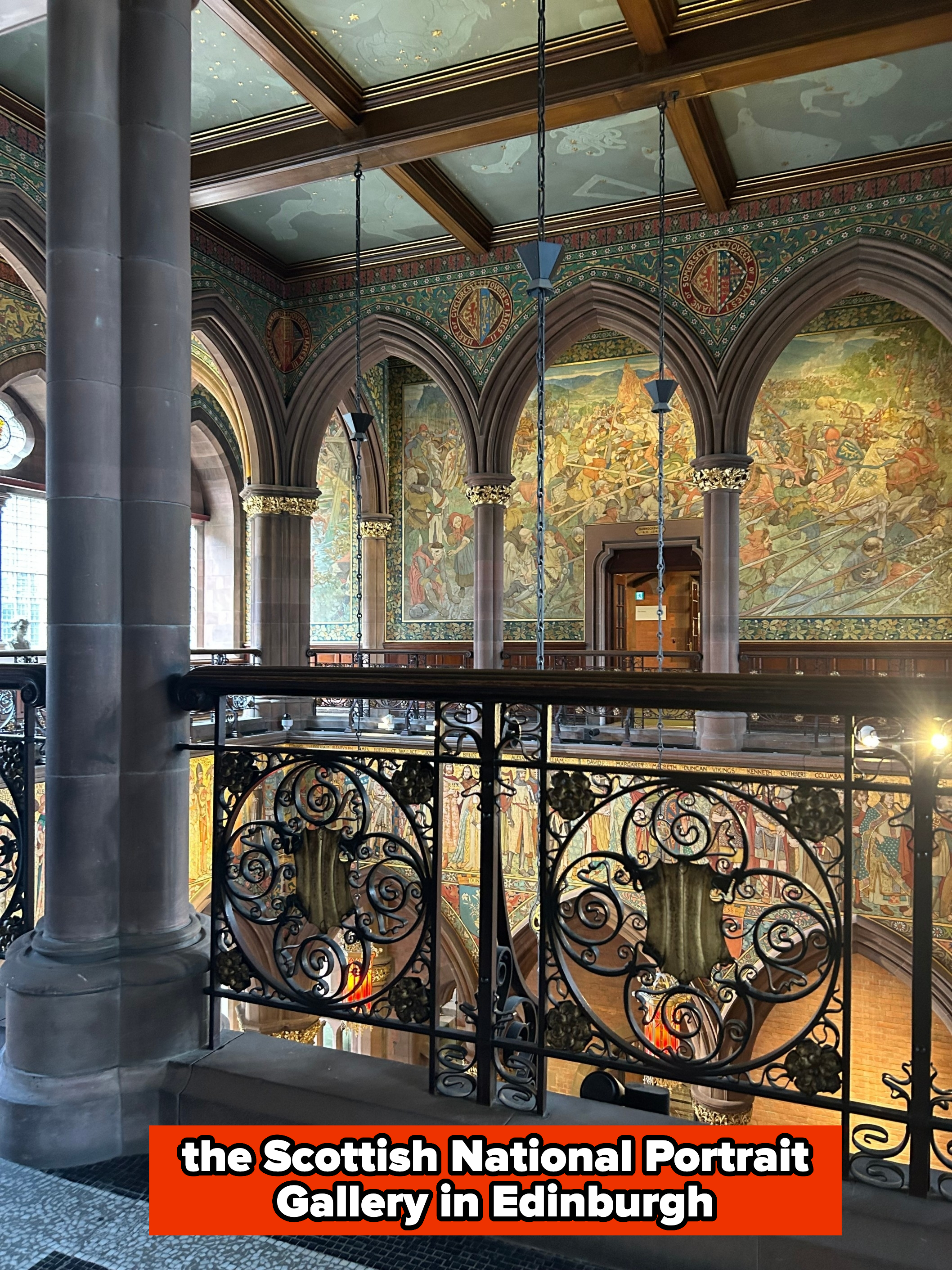 An ornate interior of a historic building featuring detailed murals, arched windows, and an intricately designed balustrade