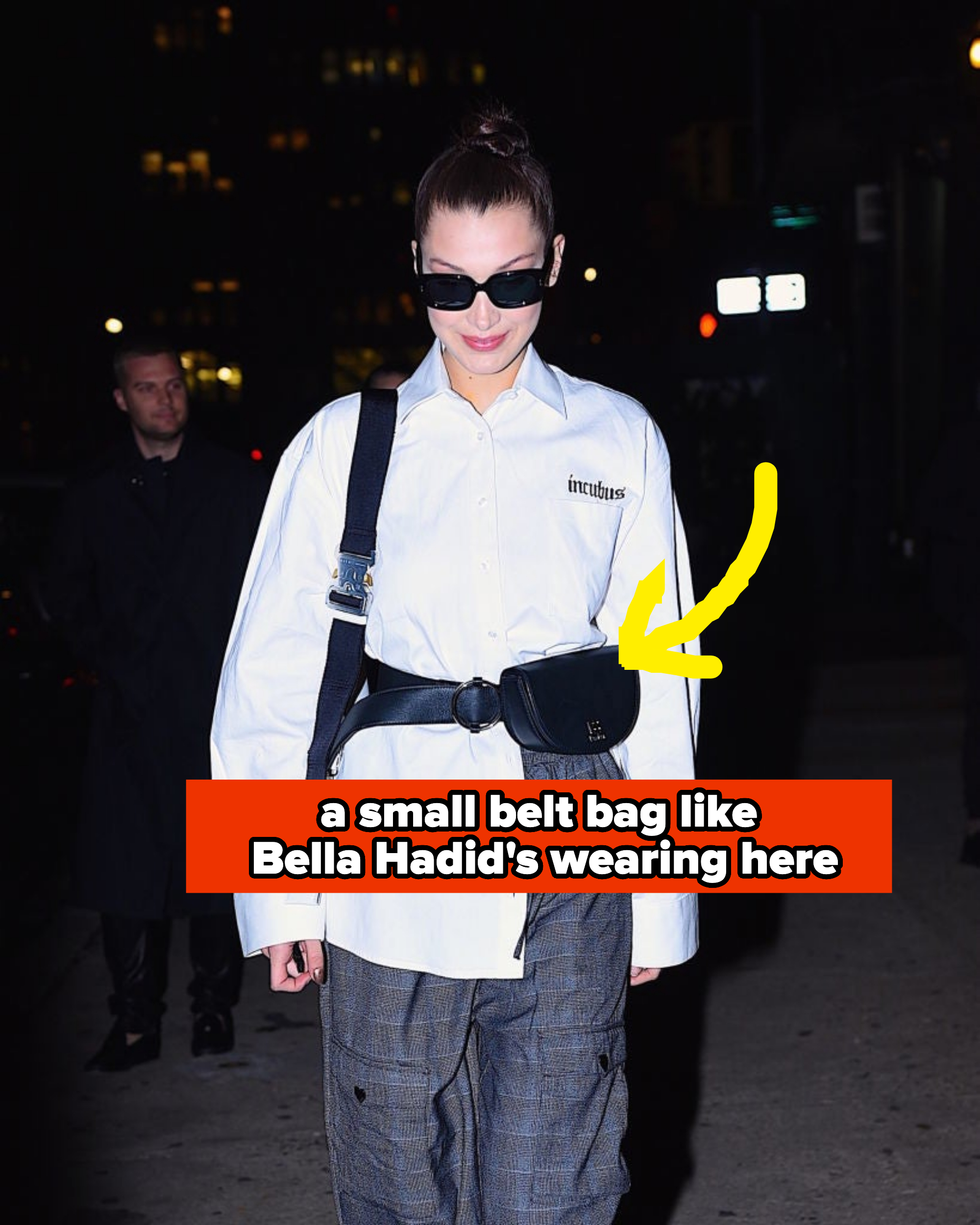Bella Hadid is seen at night wearing an oversized shirt, plaid pants, a belt bag, and sunglasses.