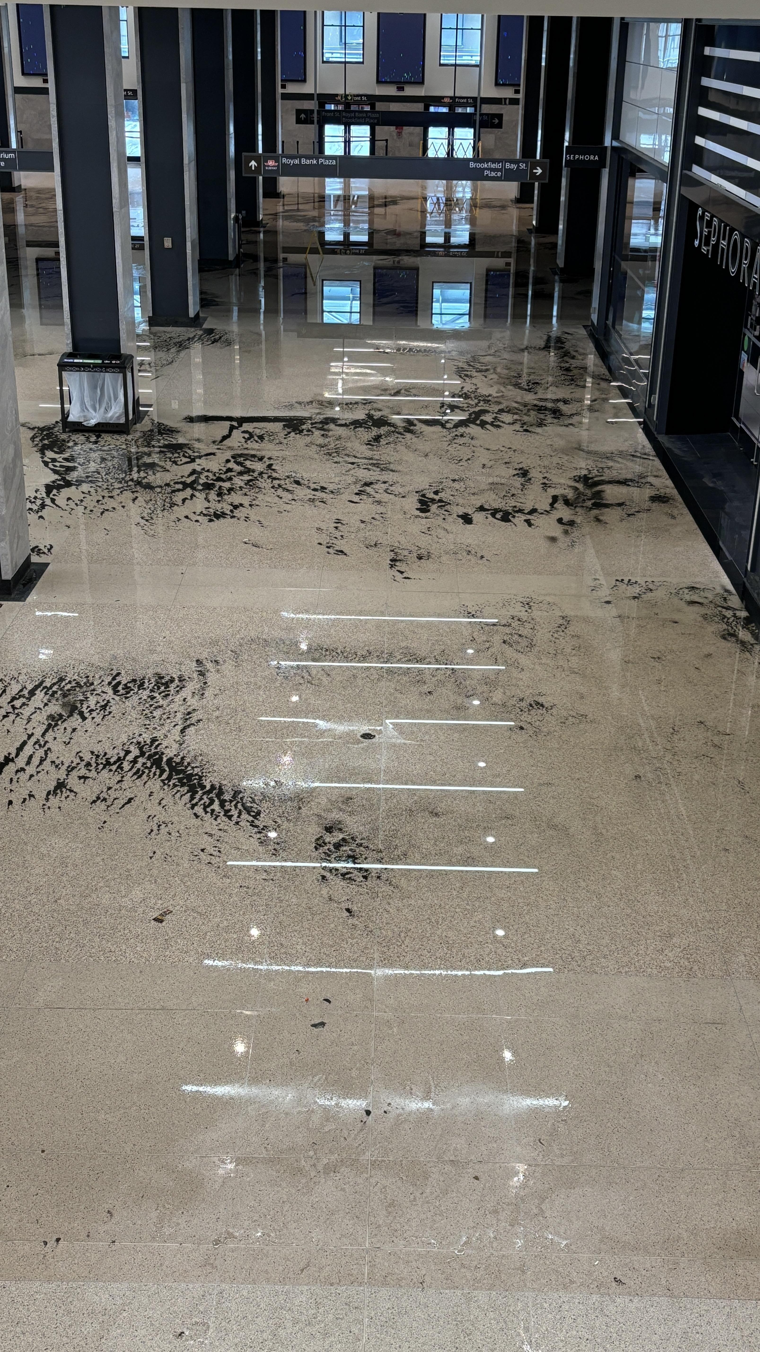 A shopping mall scene with a dirty floor and a Sephora store in the background. The floor appears to have dark patches and debris scattered around