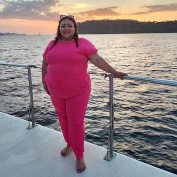 Person successful a casual outfit lasting connected a vessel deck, with a scenic sunset implicit the water successful the background