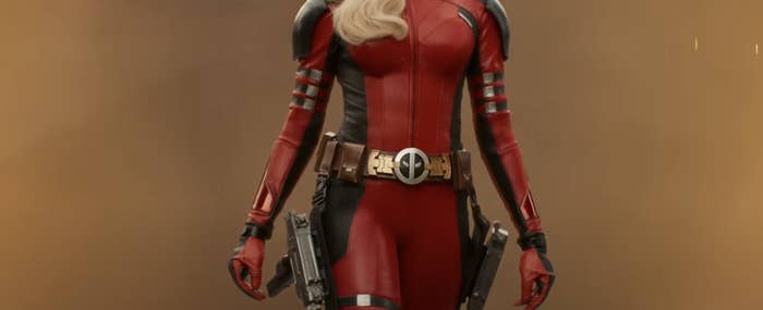 A person dressed as Deadpool in a form-fitting superhero outfit with a utility belt and holstered weapons. Face not visible