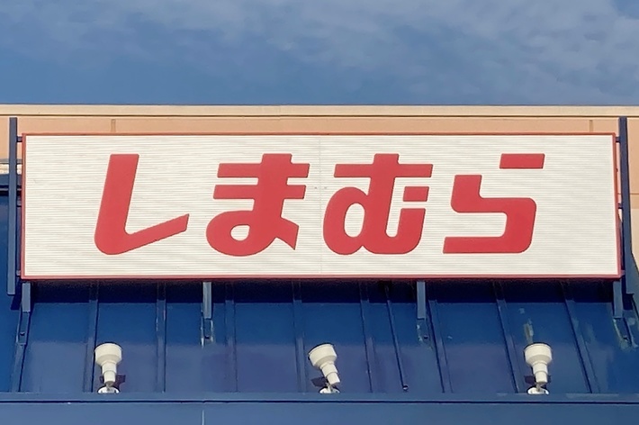 The image shows a storefront with a sign in Japanese characters above the entrance. There is an accessible parking sign visible near the bottom right