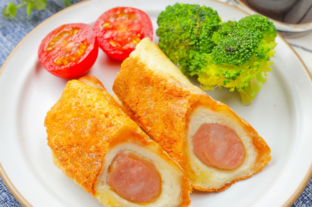 お皿に盛られたホットドッグ風春巻き、ブロッコリー、トマトの断面。