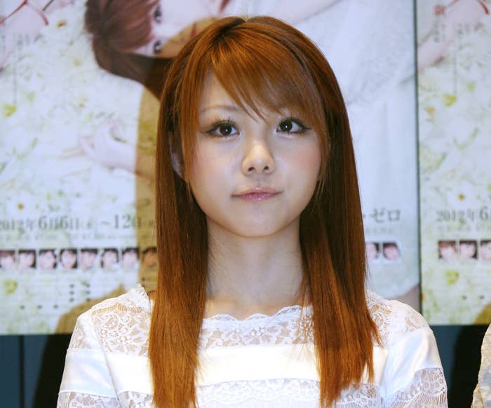 女性が白いドレスを着ている姿が写っている。背景にはポスターがある。