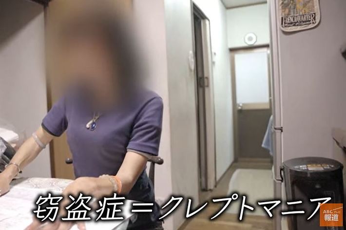 女性がテーブルに座り、何かを作業しています。右下に「窃盗症＝クレプトマニア」のテロップがあります。