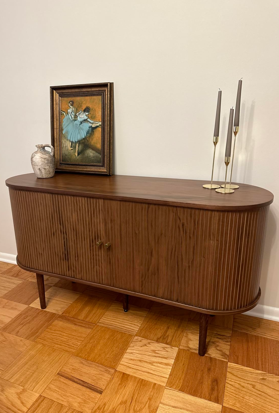 Wooden console array  with a tiny  framed painting, a ceramic vase, and 3  candlesticks. The coating  depicts dancers successful  bluish  tutus
