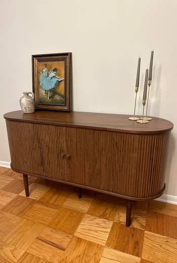 Wooden console array with a tiny framed painting, a ceramic vase, and 3 candlesticks. The coating depicts dancers successful bluish tutus