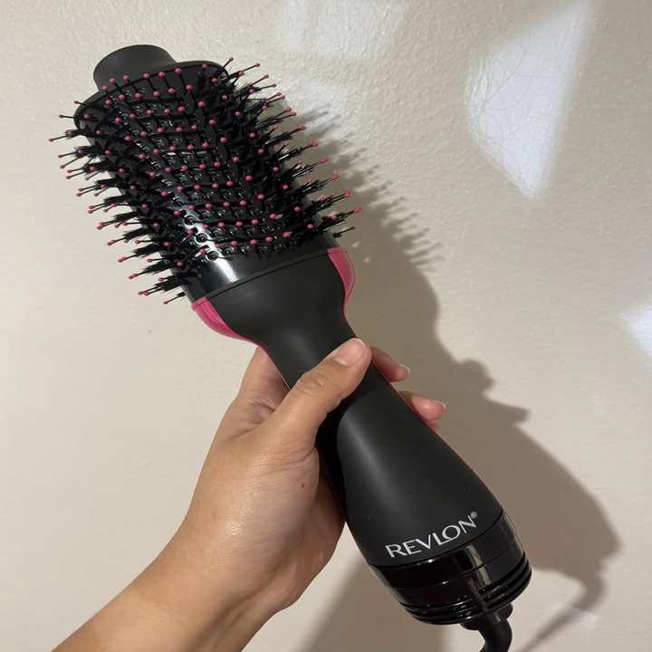 Hand holding a Revlon hair dryer brush with a textured brush head