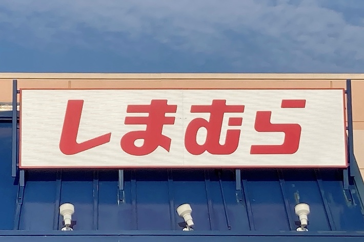 The image shows the storefront of a Shimamura retail store with its name in Japanese text above the entrance