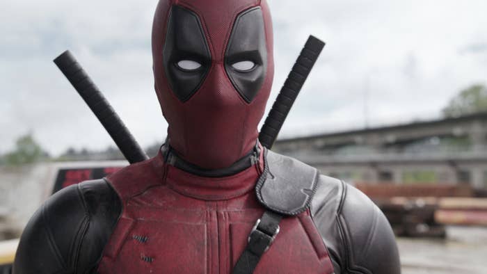 Deadpool character in full costume with red and black suit and swords on his back, looking directly at the camera