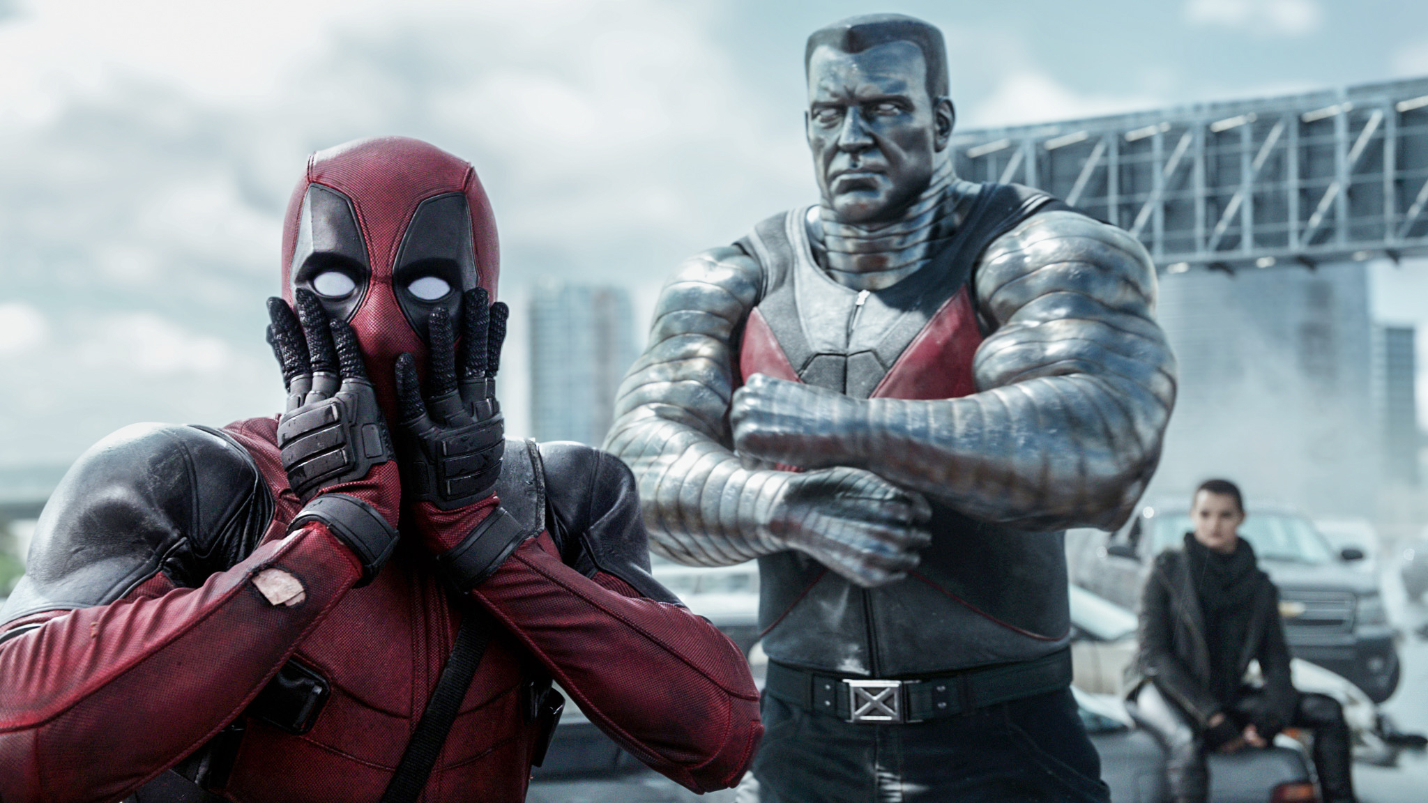 Deadpool, Colossus, and Negasonic Teenage Warhead in a scene from a movie. Deadpool is dramatically covering his face with his hands. Colossus stands with arms crossed