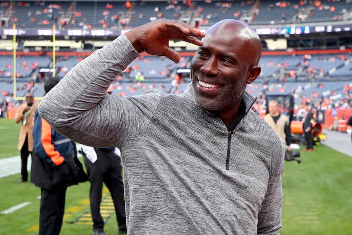 Terrell Davis smiling and saluting while standing on a football field