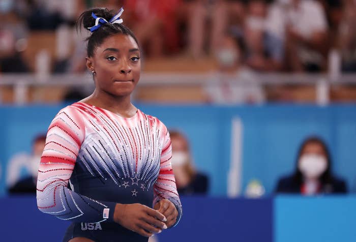 Simone Biles in a gymnastics uniform preparing for her routine during a competition