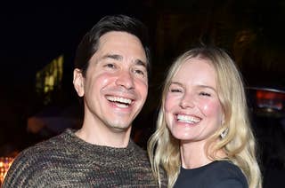 Justin Long in a casual knit sweater and Kate Bosworth in a chic outfit smile and pose together at an outdoor event
