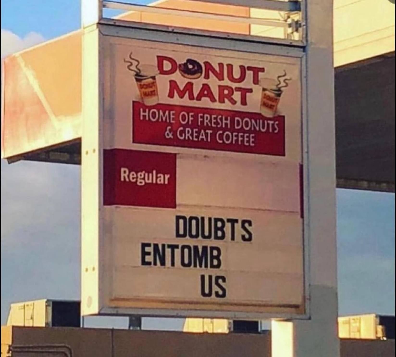 A Donut Mart sign reads: "Regular" followed by "DOUBTS ENTOMB US."