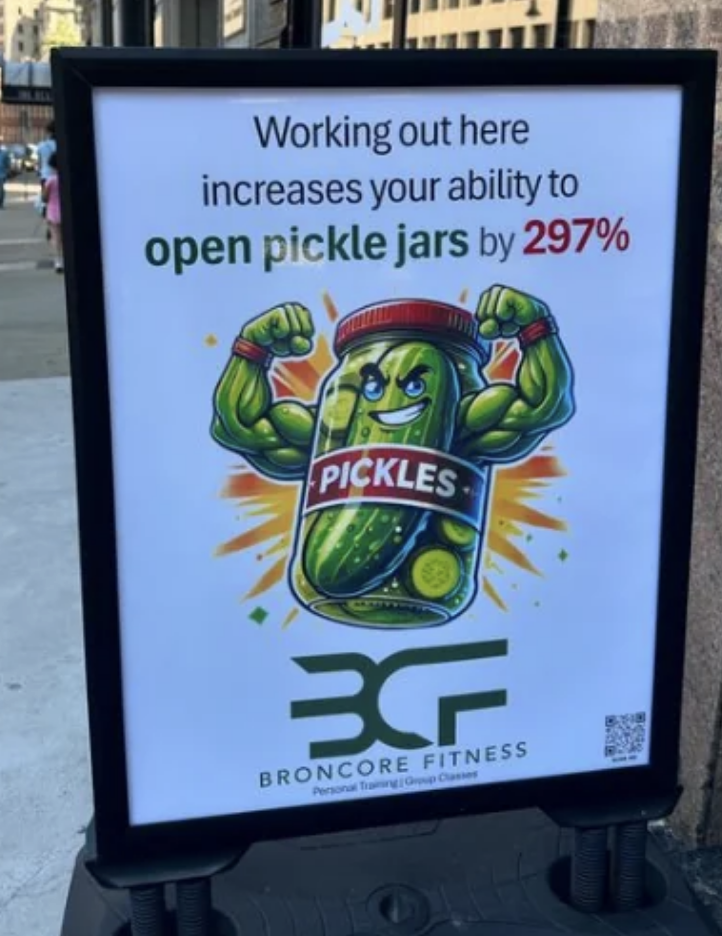 Sign for Broncore Fitness saying, "Working out here increases your ability to open pickle jars by 297%". The sign features a muscular pickle jar illustration