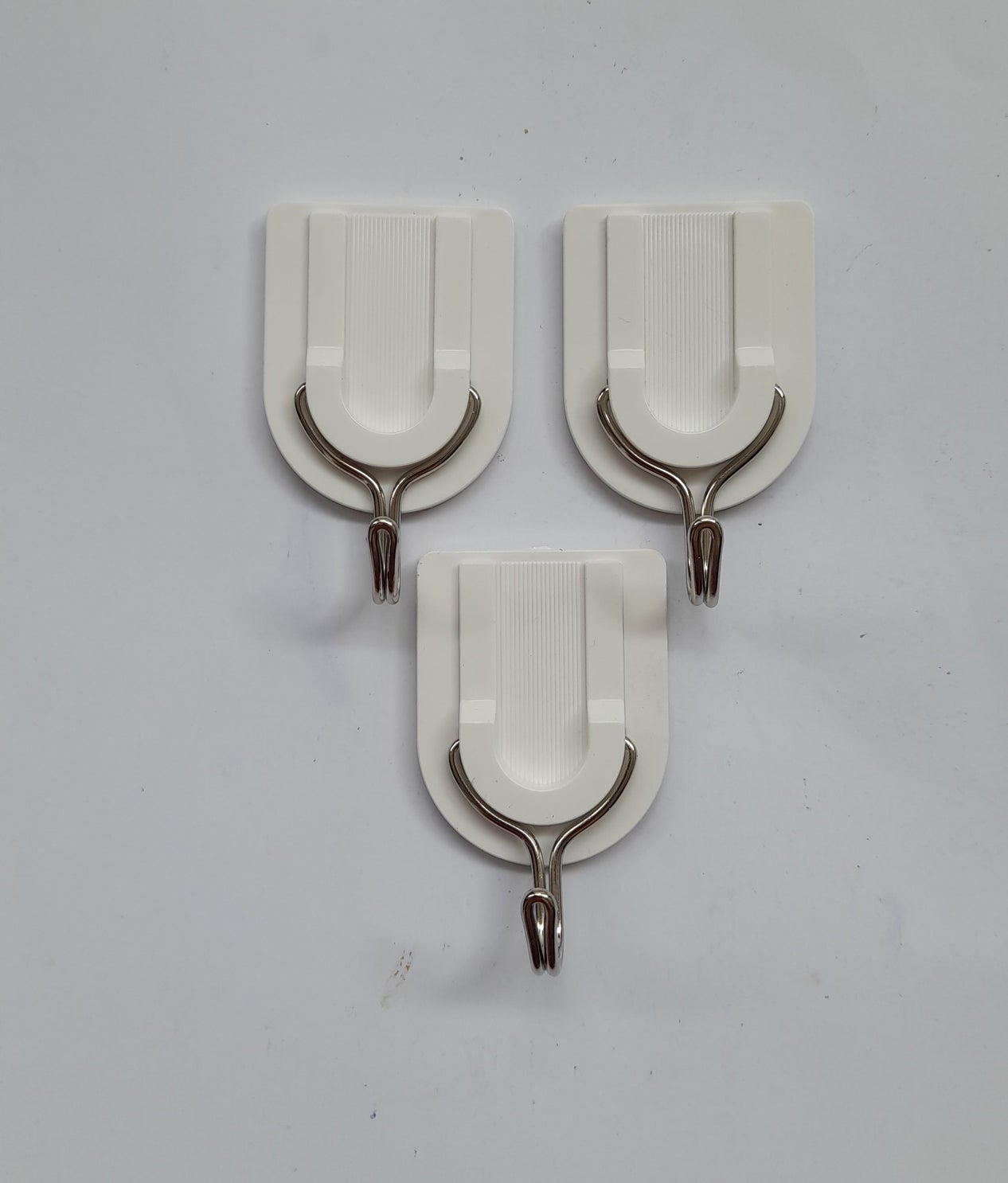 Three wall-mounted hooks with adhesive backs