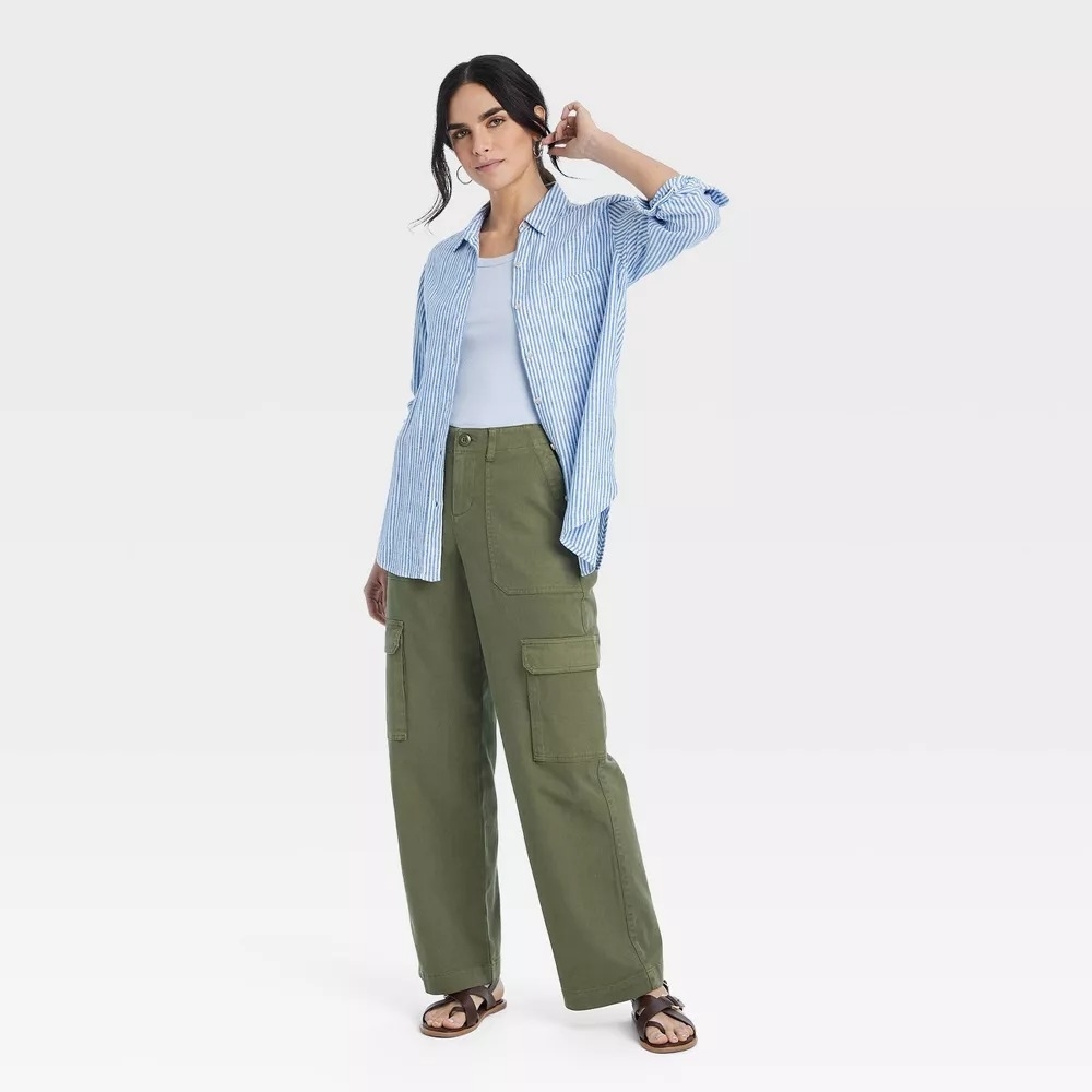 Model wearing a casual outfit of a striped button-down shirt over a white top and wide-legged cargo pants