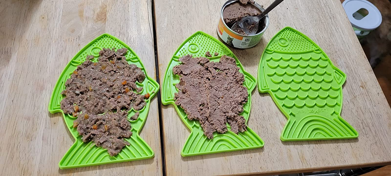 two of the green fish shaped lick mats covered in wet food