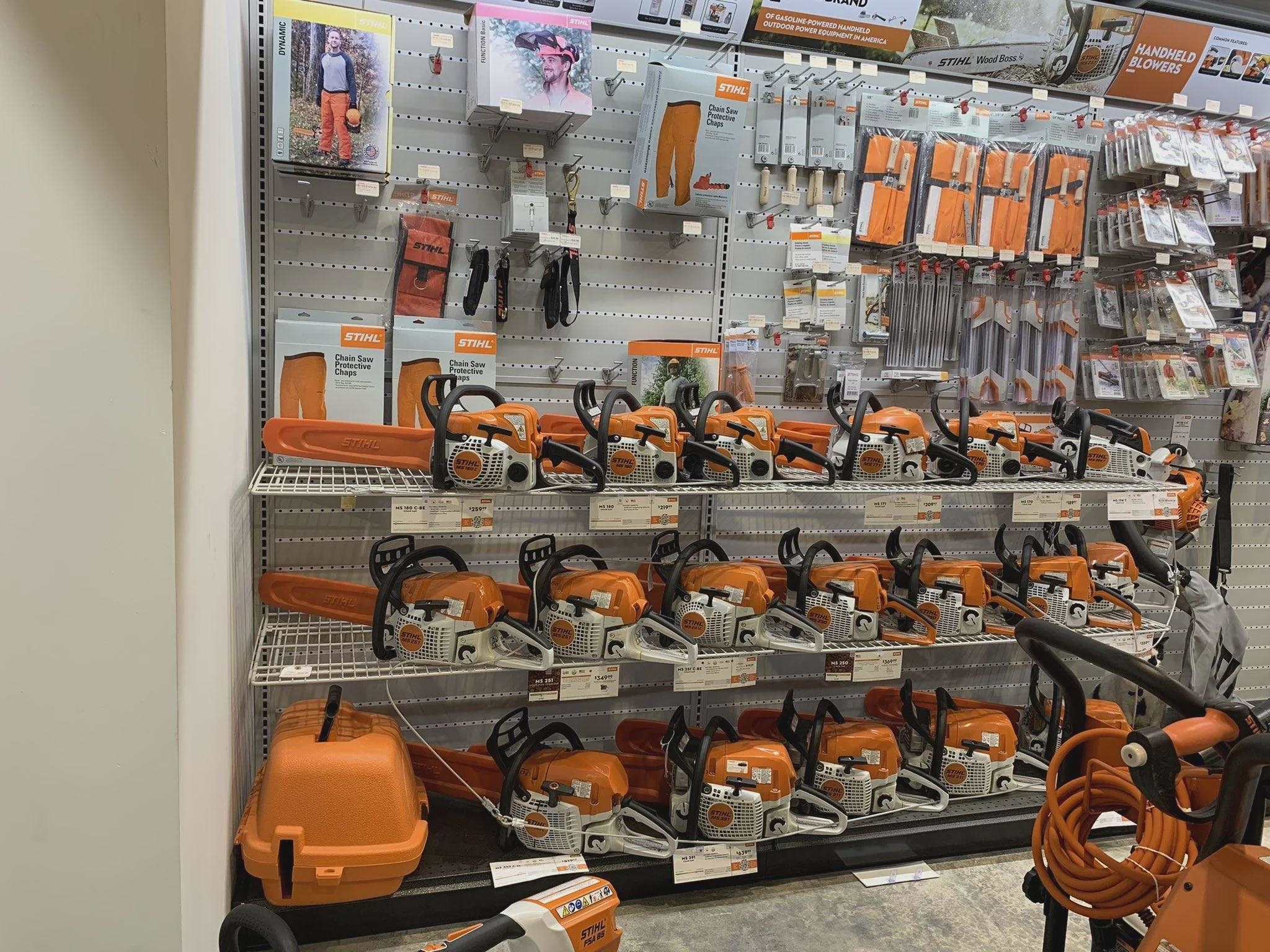 Store display shelf with various models of Stihl chainsaws, accessories, and protective gear