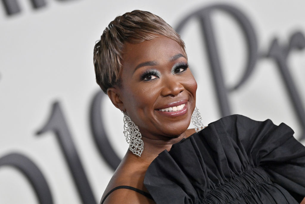 Joy Reid in a stylish off-shoulder dress with elegant, dangling earrings, smiling at a red carpet event