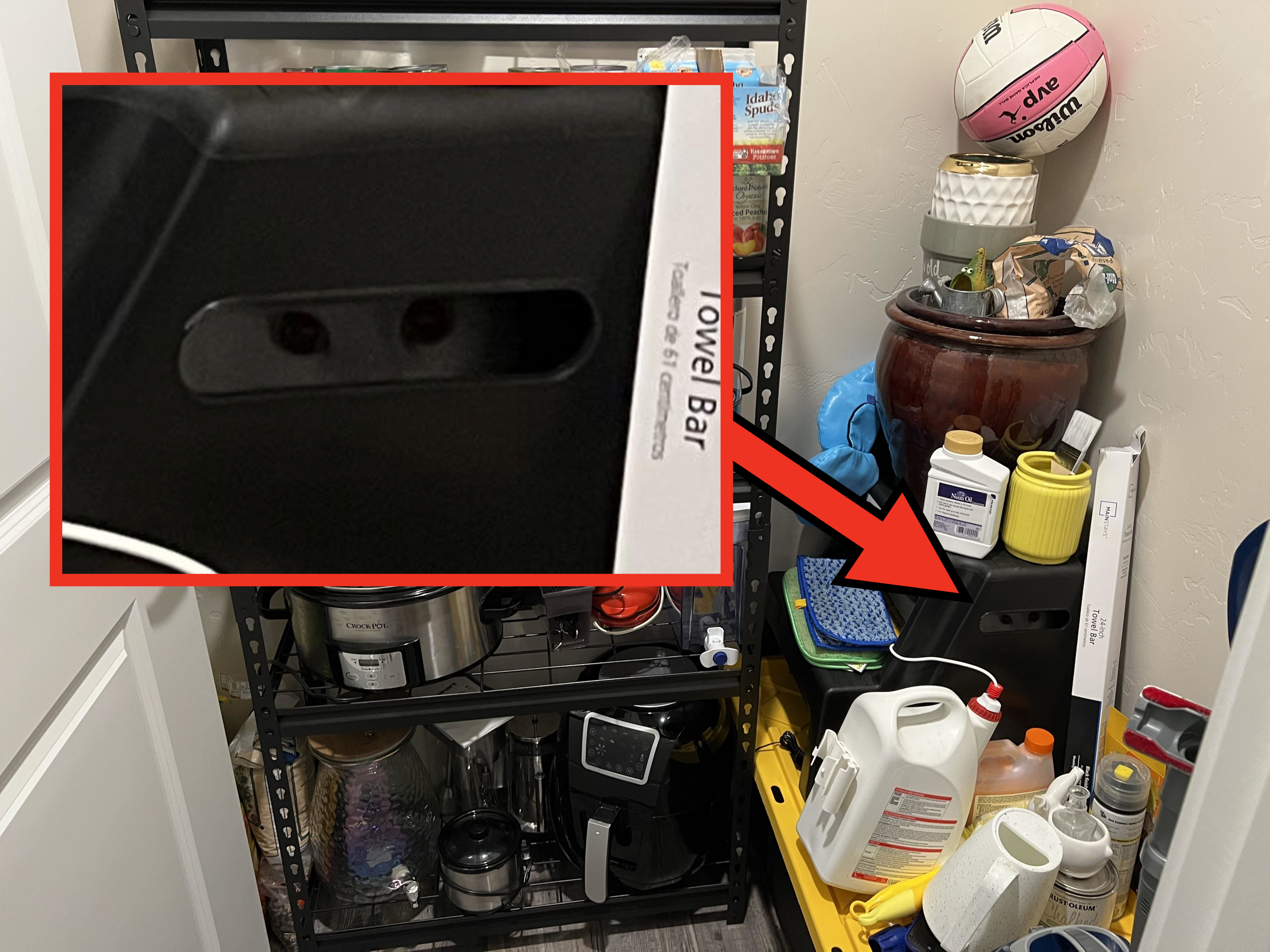 A pantry with shelves containing canned foods, snacks, paper towels, cleaning supplies, kitchen appliances, and a basketball. There are various drinks and cleaners on the floor