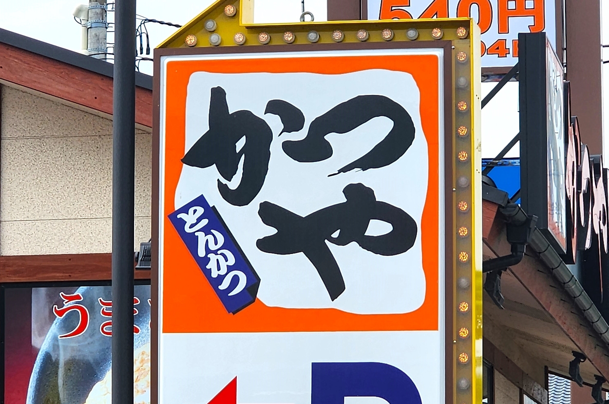 とんかつ専門店「かつや」の看板。カツ丼540円の広告も表示。