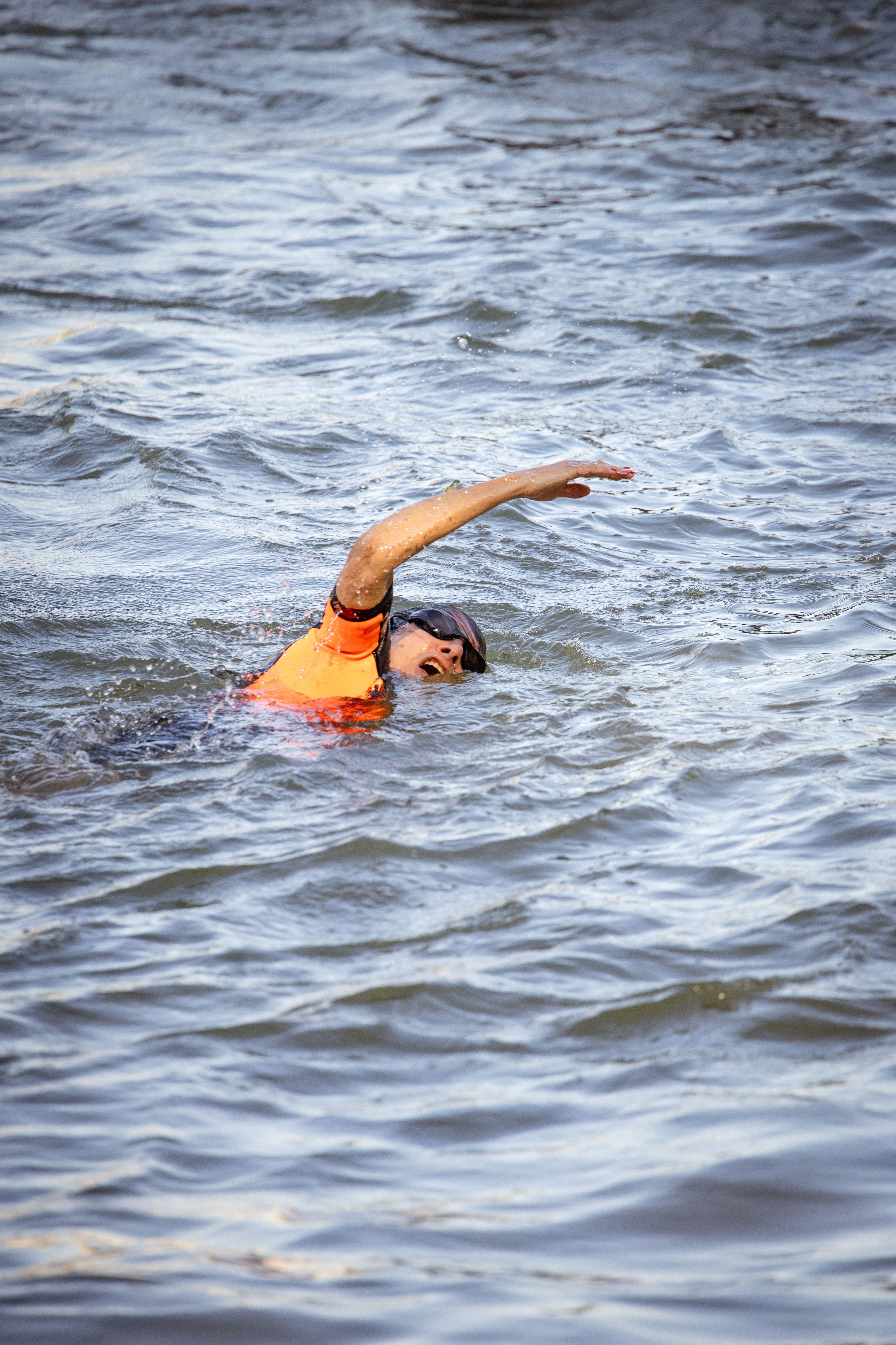 Person swimming in a body of water wearing an orange life vest