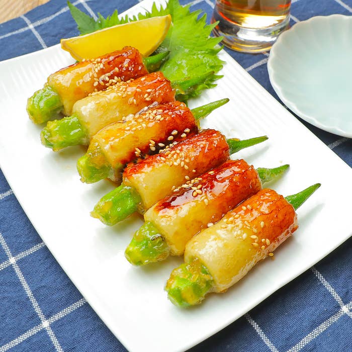 焼きオクラとごまを載せた前菜が白いお皿に並べられている。レモンのくさぎやしそが添えられている。