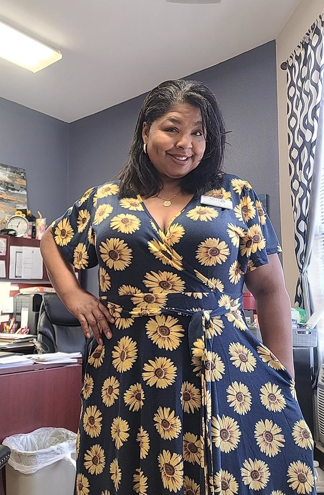 Smiling reviewer successful  a floral formal  with sunflowers, lasting  successful  an office. The inheritance  includes an bureau   table  and a partition  with immoderate   papers and decoration