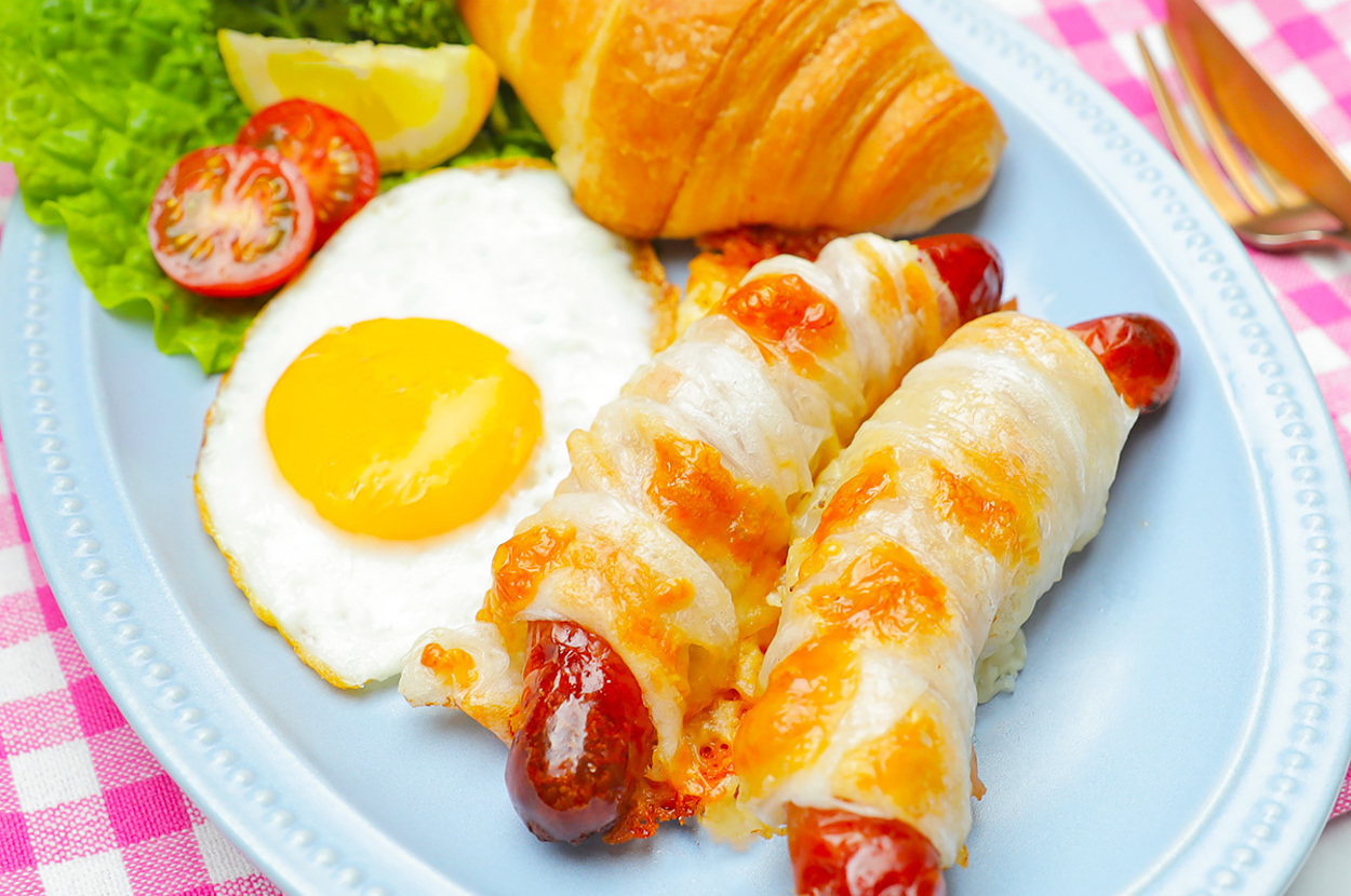 お皿にはクロワッサン、目玉焼き、焼きトマト、レタス、ソーセージが乗っています。