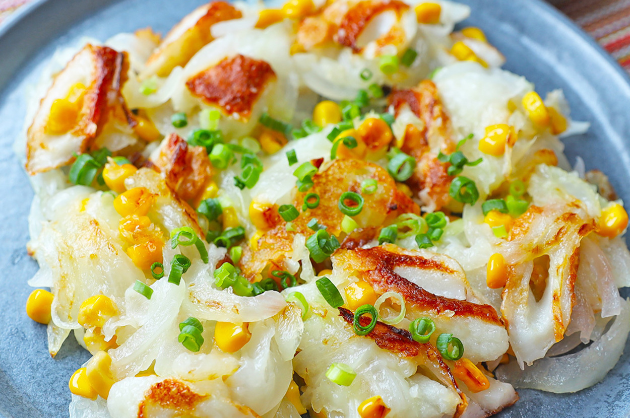 お皿に盛られた、ごま油で炒めたイカ、コーン、青ネギの一品。隣にはケチャップの入った小皿が添えられています。