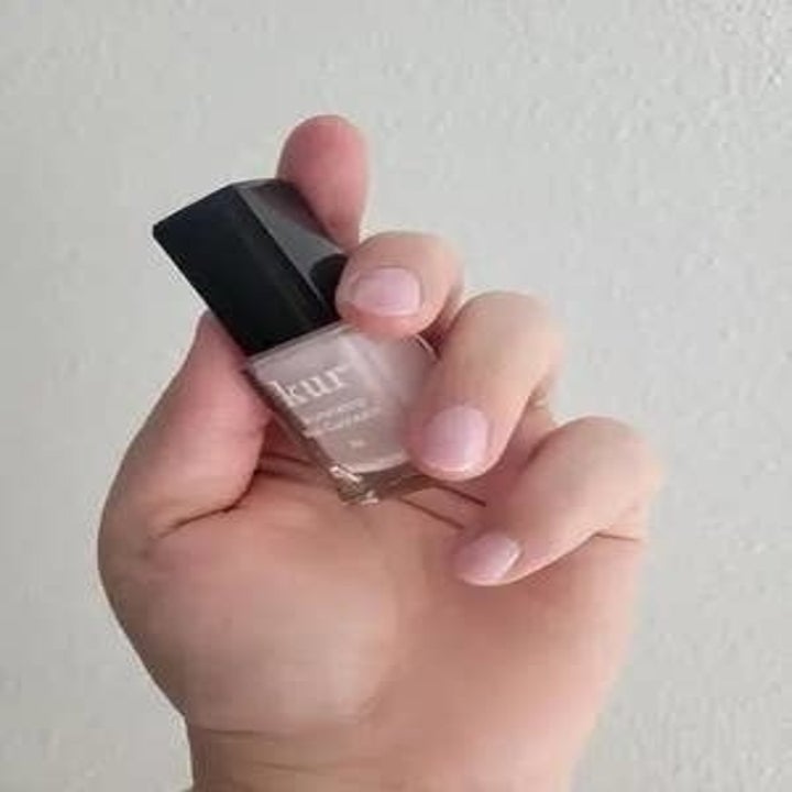Hand holding a bottle of pale pink nail polish with "Julep Brigitte" written on the bottle