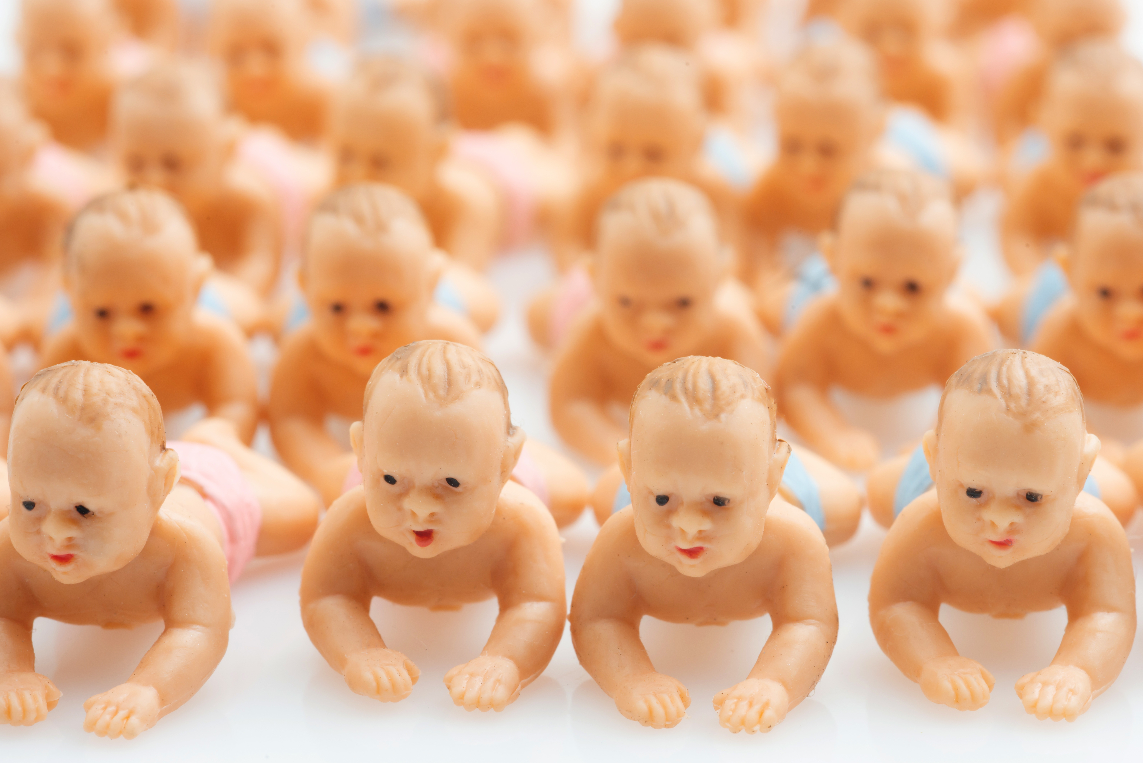 Rows of small plastic baby dolls positioned in a crawling stance, facing forward