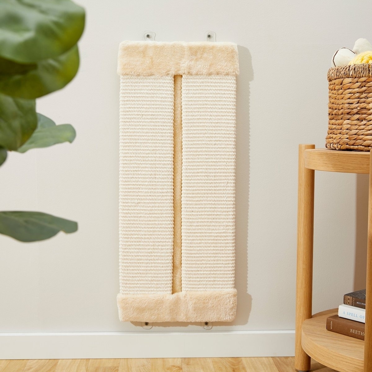 A wall-mounted beige cat scratcher with a basket of yarn and a plant in the foreground