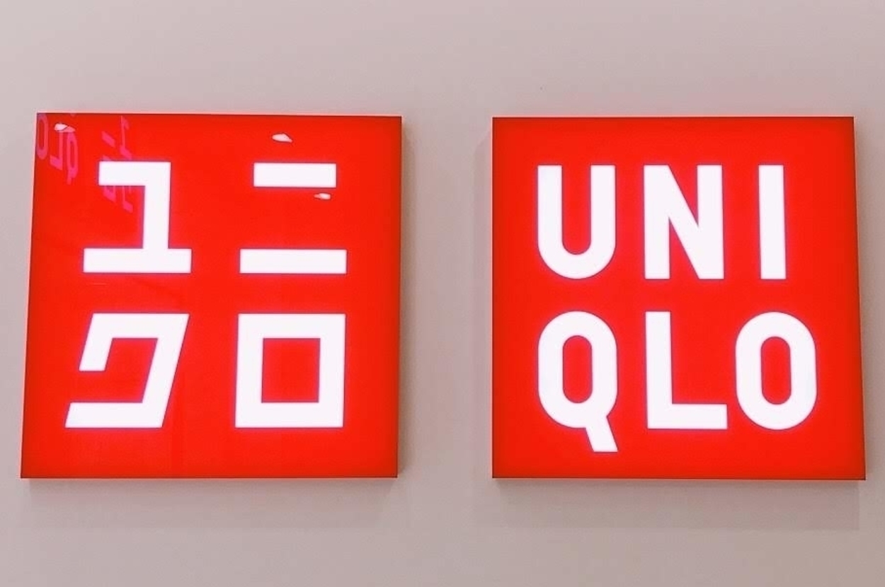 Two red signs with white text, one in Japanese characters and the other "UNI QLO," representing the Uniqlo brand