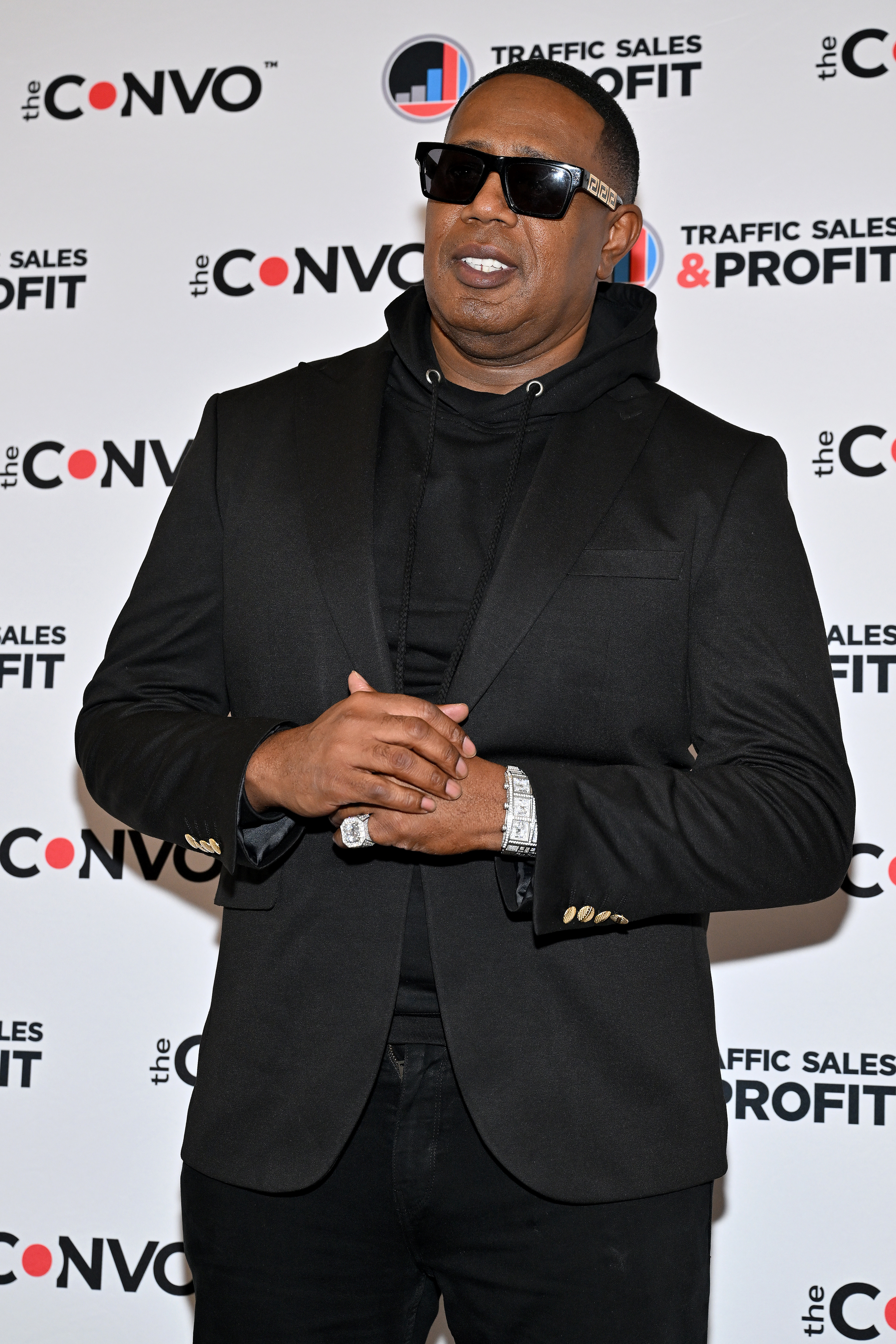 Master P wearing a black suit, hoodie, and sunglasses at the Traffic Sales &amp;amp; Profit event backdrop