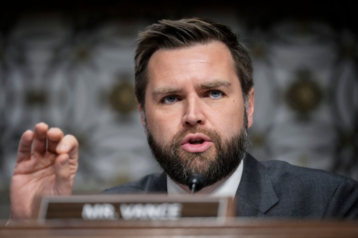 J.D. Vance is speaking, wearing a suit and tie, with a focused expression during a formal event