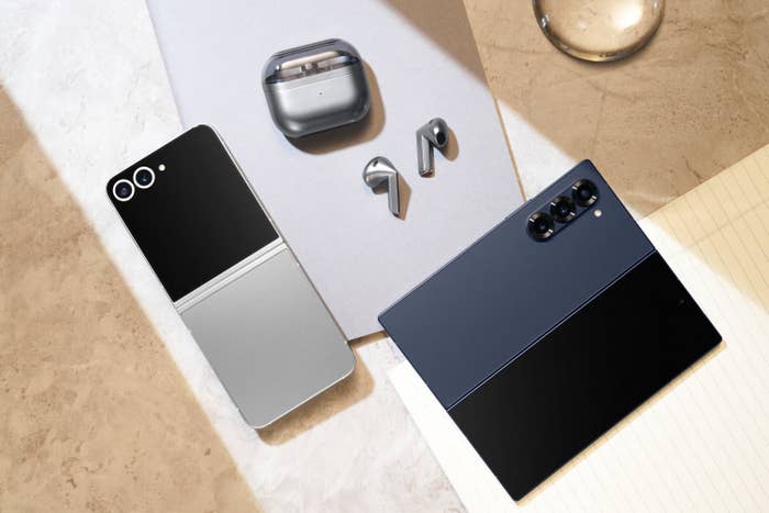 A photo showcasing various electronic devices including a smartphone, a flip phone, wireless earbuds, and a tablet placed on a flat surface