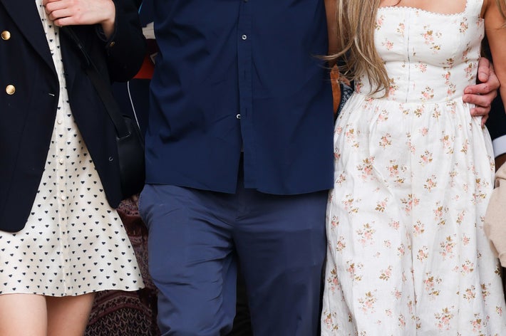 Ben Affleck, Jennifer Lopez in a floral dress, and a masked woman in a polka dot dress and blazer walking together with people in the background