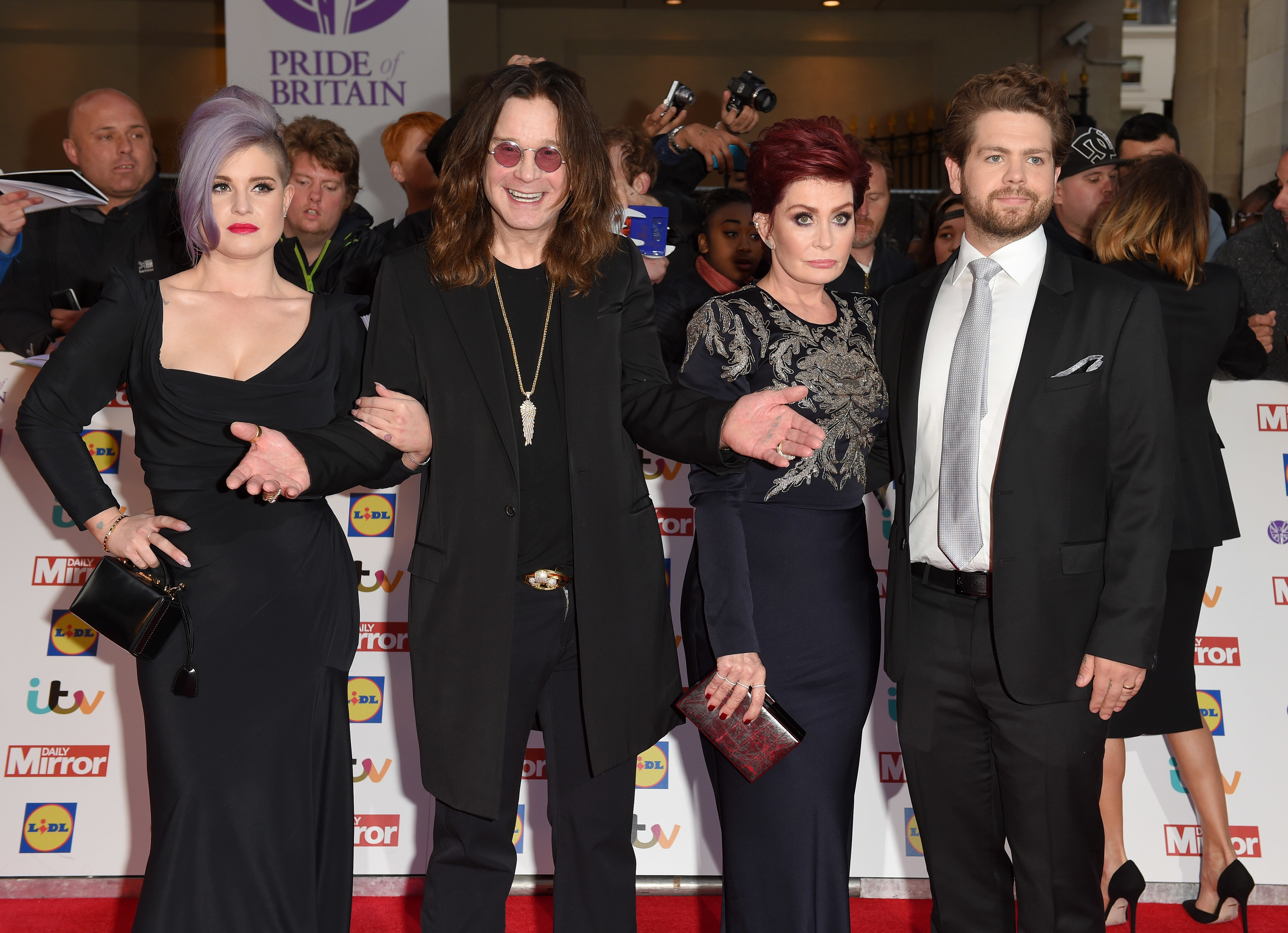 Kelly Osbourne, Ozzy Osbourne, Sharon Osbourne, and Jack Osbourne on the red carpet, posing for photos. They are dressed in formal attire