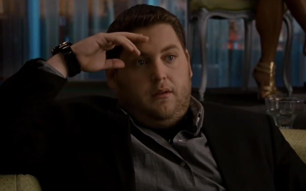 Jonah Hill sitting on a couch in a thoughtful pose