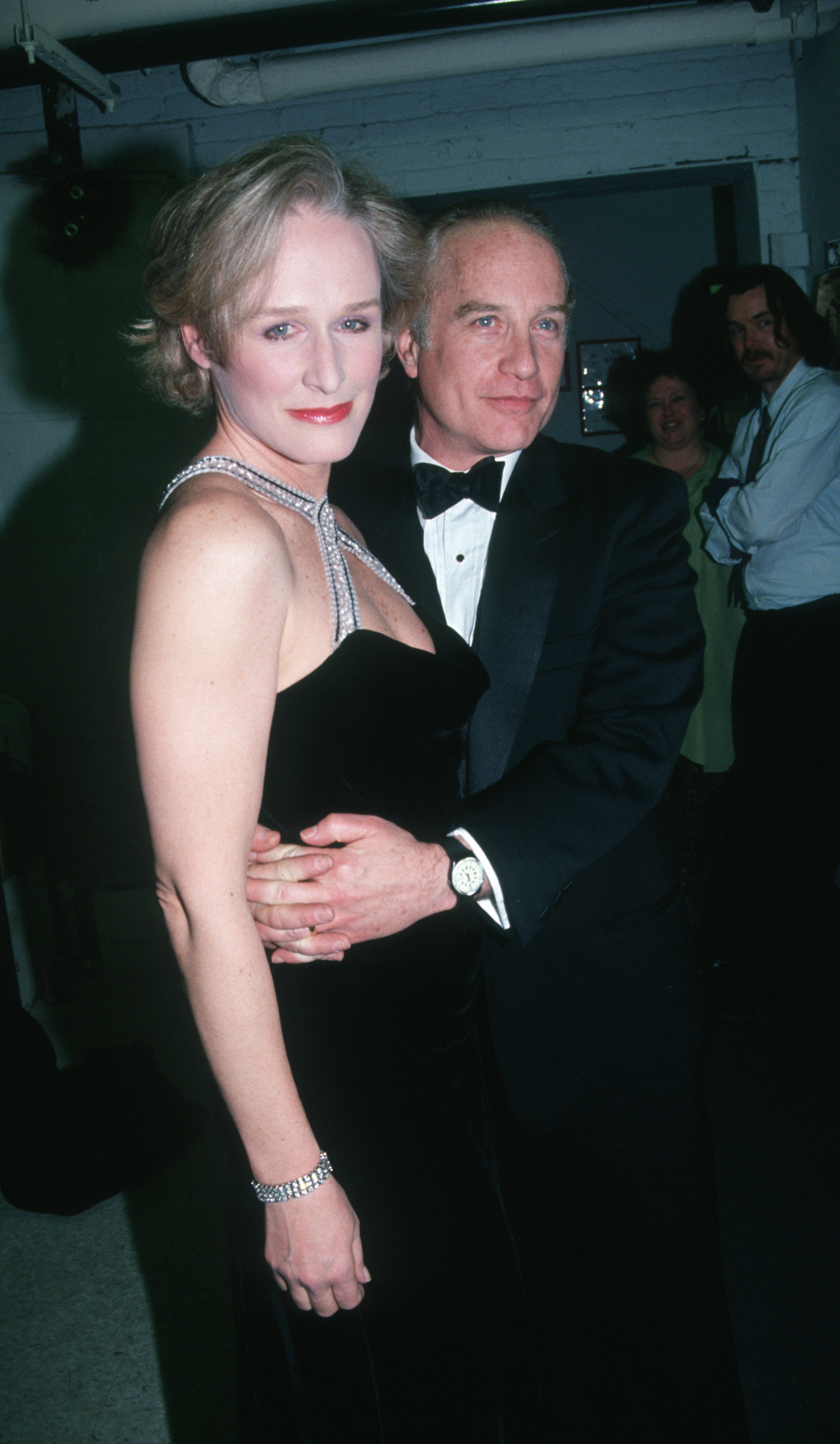 Glenn Close and Richard Dreyfuss smile, posing together. Glenn wears an elegant evening dress, and Richard is dressed in a tuxedo
