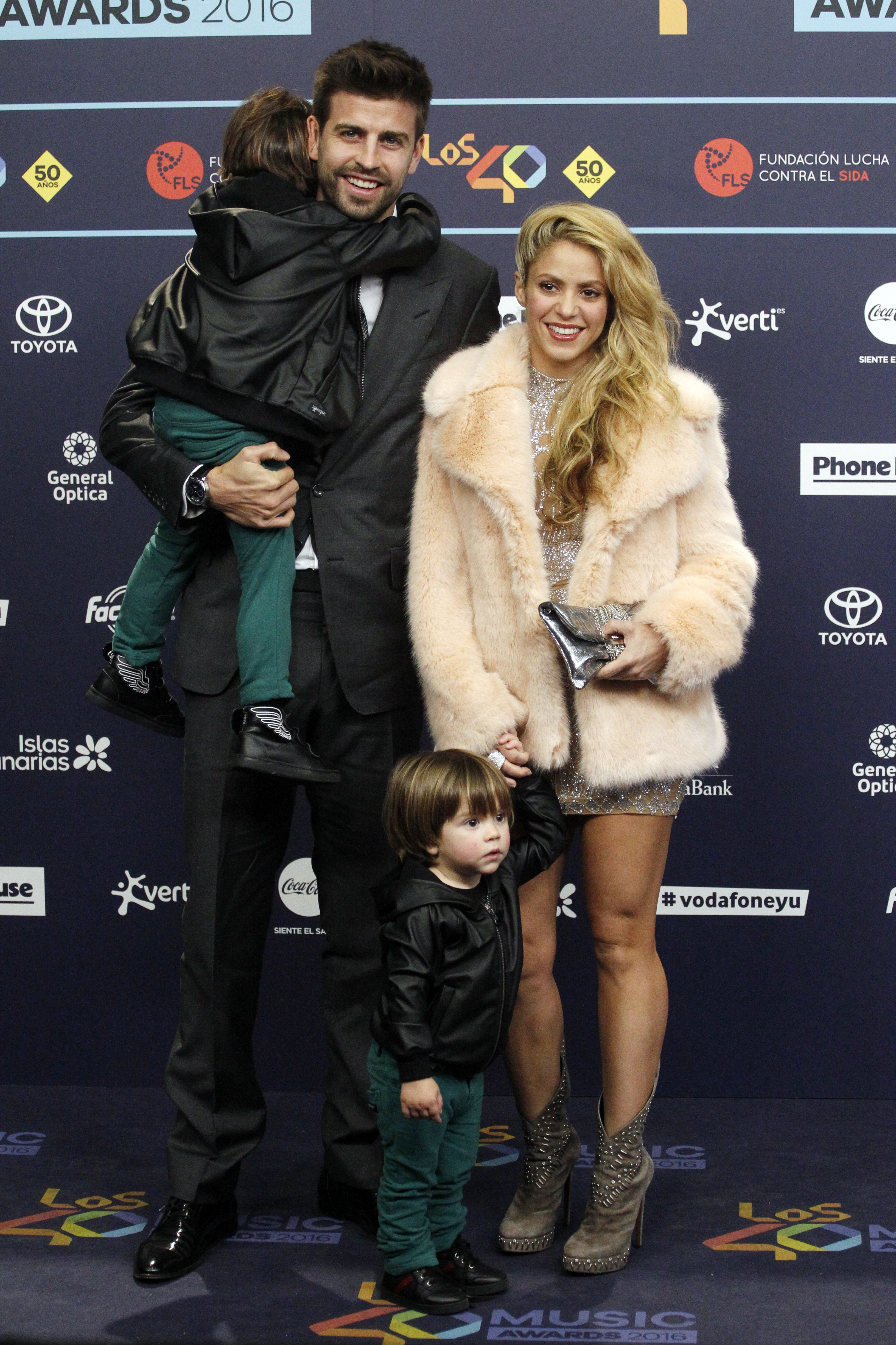 Gerard Piqué and Shakira pose on the red carpet with their two children. Gerard is in a suit, Shakira in a fur coat and sparkly dress