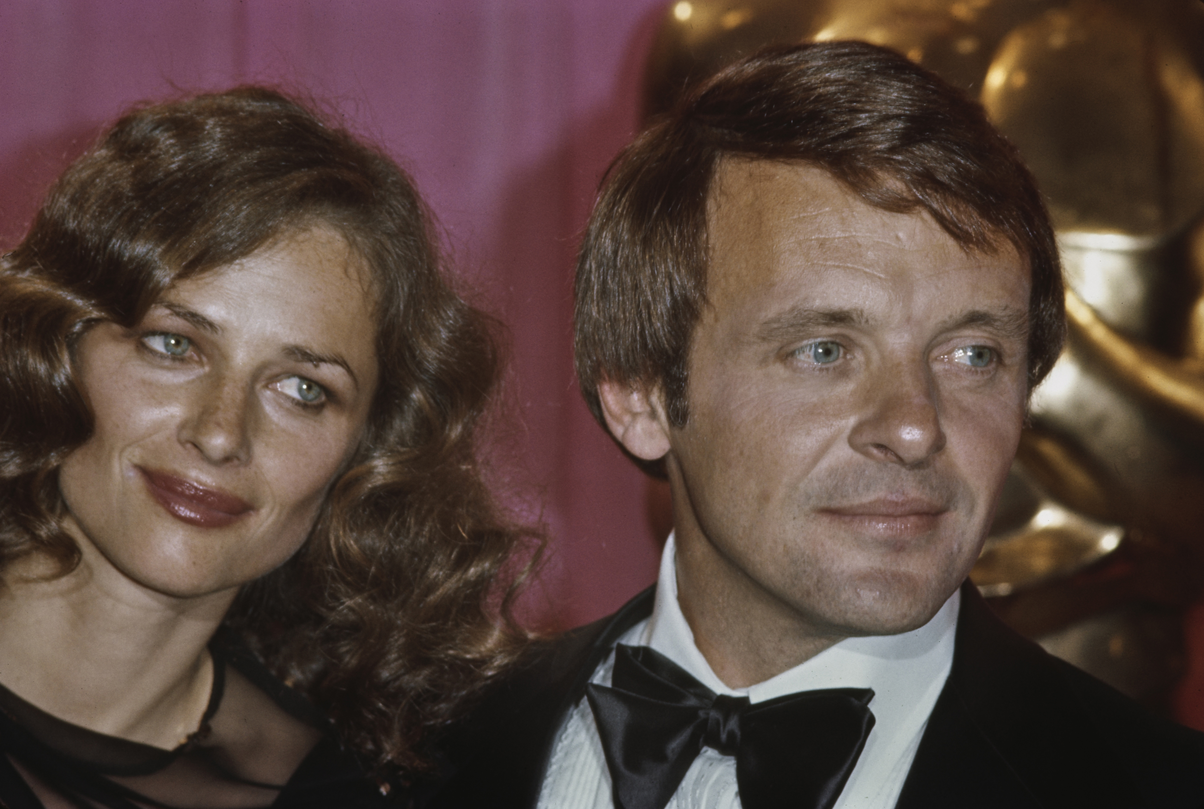Unknown people at a formal event. The man is wearing a tuxedo and bow tie, and the woman has curly hair and is dressed elegantly