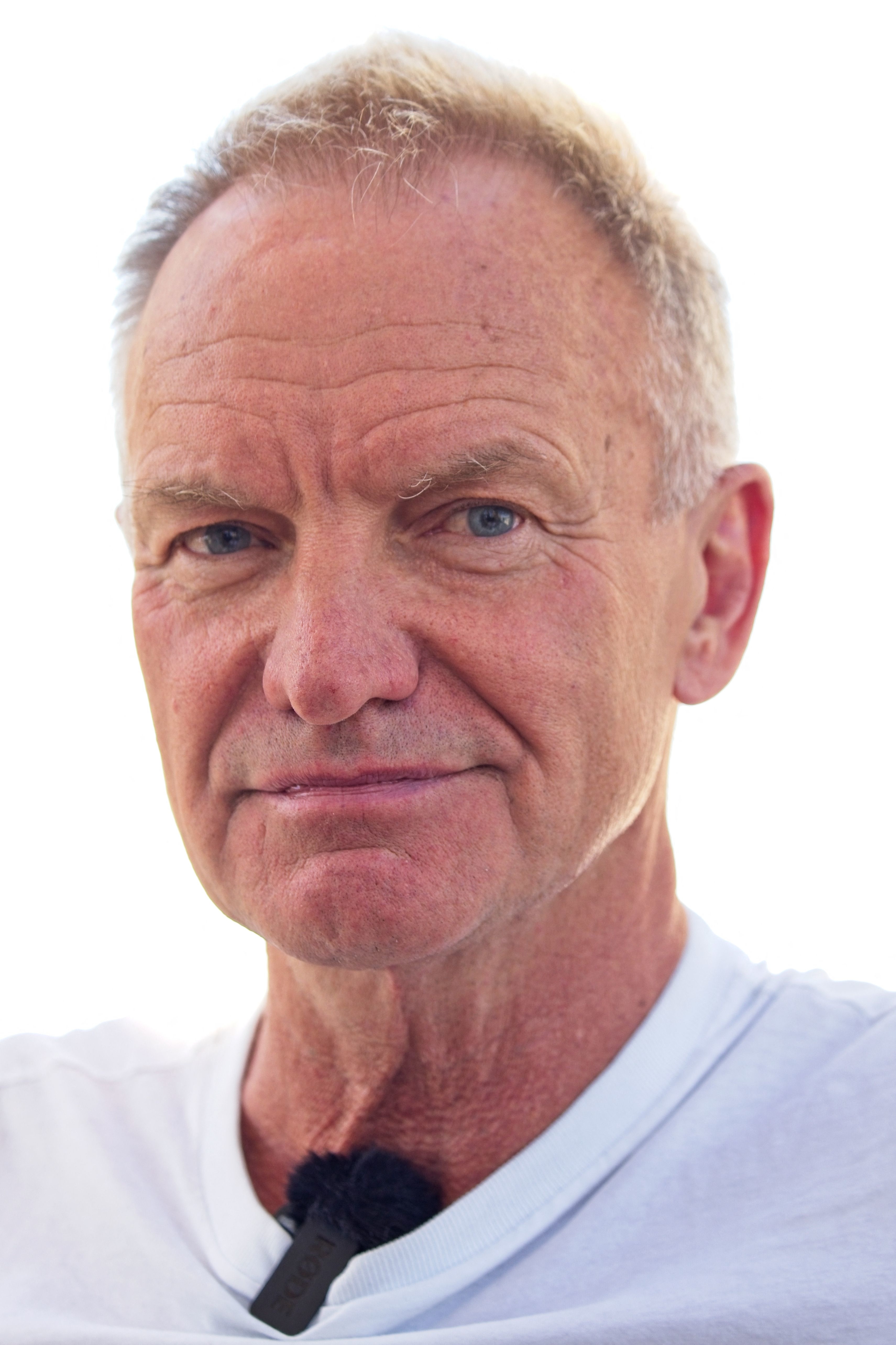 Sting in a white shirt, smiling subtly at the camera
