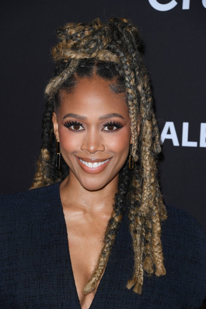 Nicole Beharie long dreadlocks styled in an updo, smiling at the camera in a formal dark outfit at a celebrity event. Names of persons not provided