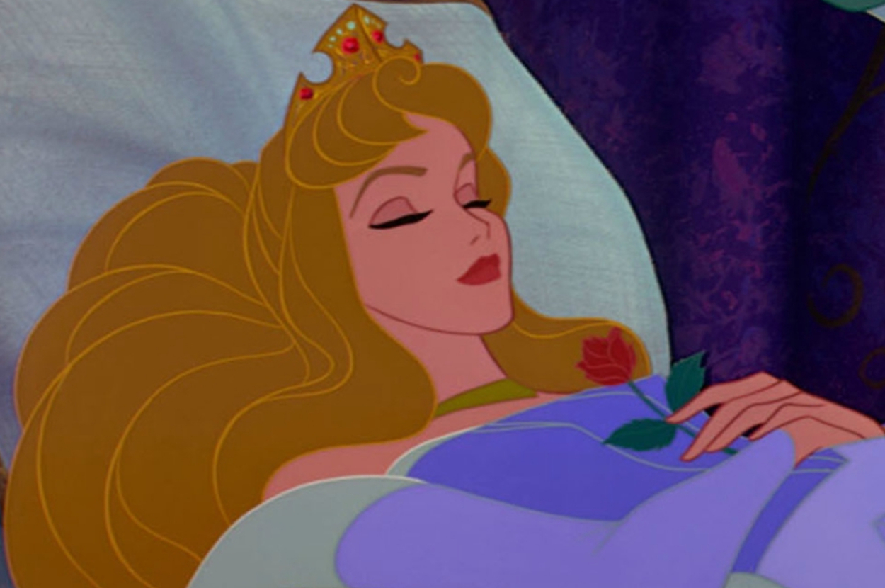 Aurora from Sleeping Beauty is lying in bed, eyes closed, wearing a crown and holding a single rose